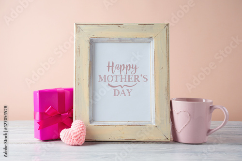 Mother's day concept with photo frame mock up, gift box and coffee cup on wooden table.