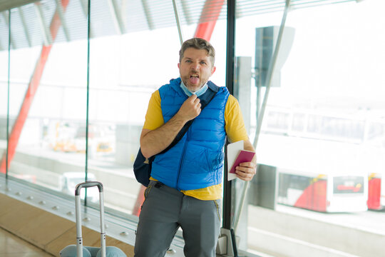 Holiday Travel And Tourism During Covid19 - Young Attractive Man Annoyed And Tired Of Wearing Face Mask At Airport Departures Lounge Holding Passport