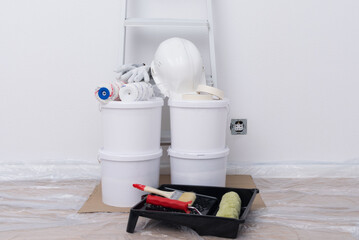 materials and tools in a pile, against a white wall before work, buckets, rollers, brushes © kurgu128