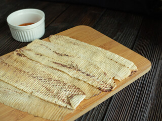 Mashed squid on wood dish and brown wooden table, seafood snack. Barbecue taste. Favorite food from Thailand.