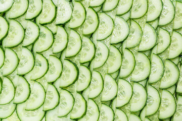 Fresh green slices of cucumber as background.