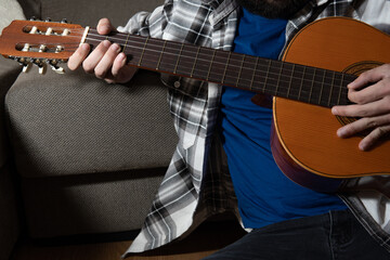 Fototapeta premium Body of a boy in a shirt and T-shirt playing a Spanish guitar