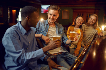 Four friends drinks beer at the counter in bar