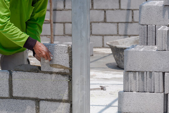 Cropped image of bricklayer making interior brick wall inside of house construction site