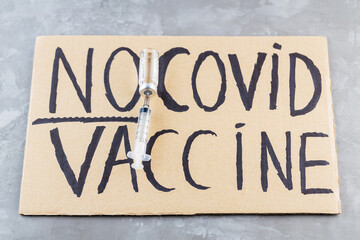 'No covid vaccine' protestive placard. Anti-vaccination poster, vaccine bottle and syringe