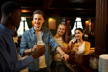 Friends with beer make a toast at counter in bar