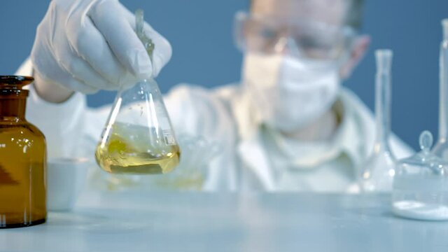 Chemical laboratory food supply. GMO Genetically modified products in the laboratory. A lab technician in a white coat holds nitric acid in his hand.