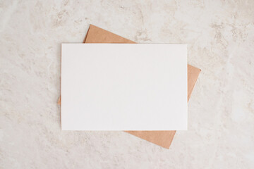 Blank card mock up. Layout of sheet of paper on craft envelope and marble texture. Horizontal canvas template for greeting, wedding cards, invitations. Natural beige colors.