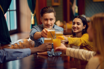 Cheerful friends clink glasses at counter in bar