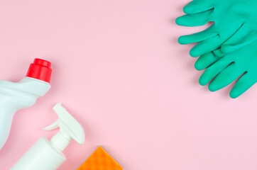 Cleaning products on a pink background. White bottles with detergents and cleaning products, sponges and gloves on a rose background with place for text. Cleaning tools company concept.