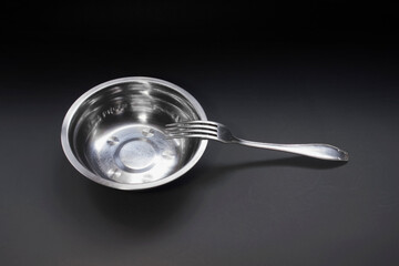 empty aluminium bowl and fork on black background