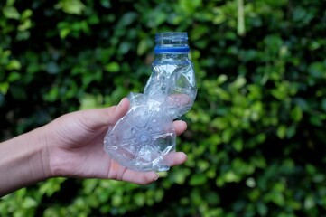 Someone's hand shows how to dispose of squeezed plastic bottles to make it more environmentally friendly 