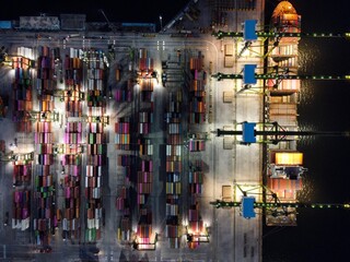 Aerial view of Container ship loading and unloading in deep sea port, logistic import and export freight transportation by container ship in open sea at night. Jakarta, Indonesia, April 12, 2021