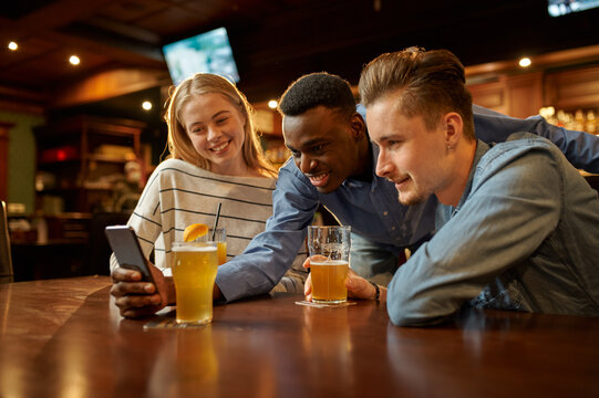 Friends look at photos on phone in bar