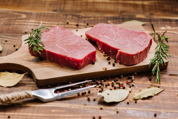 Fresh raw meat steaks on wooden background