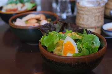Vegetable salad bowl on wooden table. Fresh green salad in restaurant. Vegetable salad with bacon, mushrooms, eggs.