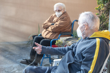 Elderly man and woman waiting outdoor to receive Covid-19 Vaccine, thinking about possible side...