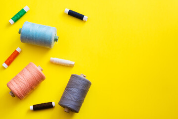 Multi-colored reels with threads on a bright, colorful background. Top View