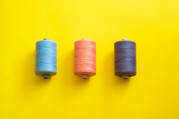 Multi-colored reels with threads on a bright, colorful background. Top View