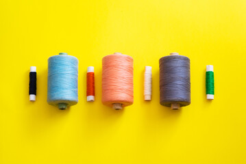 Multi-colored reels with threads on a bright, colorful background. Top View
