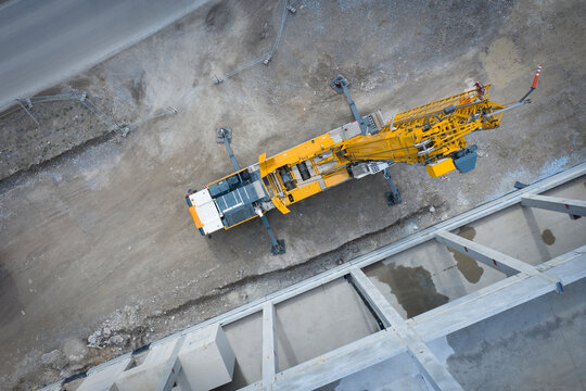 View from above on large heavy truck crane in front of concrete scaffolding of an industrial hall