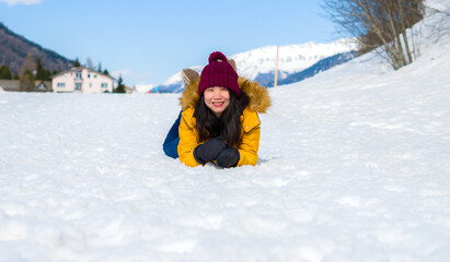 Fototapeta na wymiar Winter holidays in the snow - lifestyle portrait of young happy and beautiful Asian Japanese girl enjoying playful at frozen lake in snowy mountains at Swiss Alps