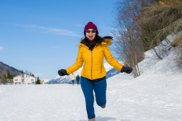 Fototapeta na wymiar Winter holidays in the snow - lifestyle portrait of young happy and beautiful Asian Korean girl enjoying playful at frozen lake in snowy mountains at Swiss Alps