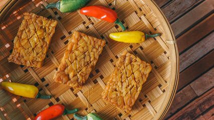 Fried tempeh decorated with chilies leaves on woven bamboo. selective focus - indonesian food,...