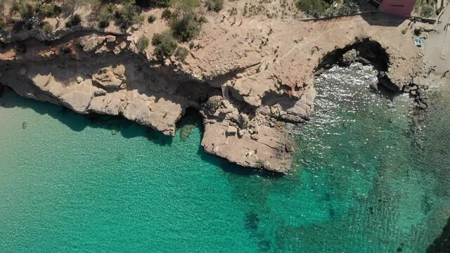 Aerial view from the sea to the land. Beautiful beach at Cala Salada, Ibiza. Blue water and green trees