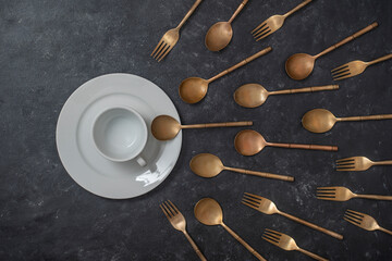 White ceramic plate, cup and brass forks and spoons look like sperm competition. Spermatozoons floating to ovule. Concept of fertilization, pregnancy and contraception