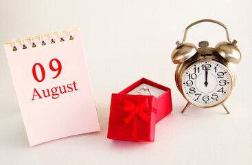 calendar date on light background with red gift box with ring and alarm clock with copy space....