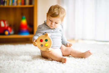 Adorable baby girl playing with educational toys . Happy healthy child having fun with colorful different wooden toy at home. Early development for children with nature toy.