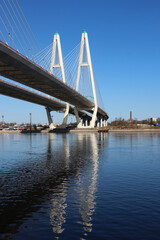 View of the cable-stayed bridge pylons and a fragment of the highway with reflexes in the water
