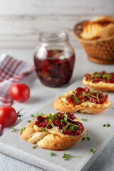 Sandwich with homemade mayonnaise, sun-dried tomatoes and micro greens, served on a board on a gray background
