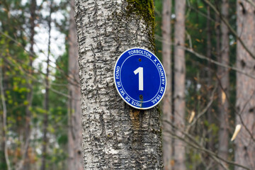 Trail marker along the Torbolton Cross Country Ski Trail in Ontario, Canada during the spring - round blue sign for trail  number 1