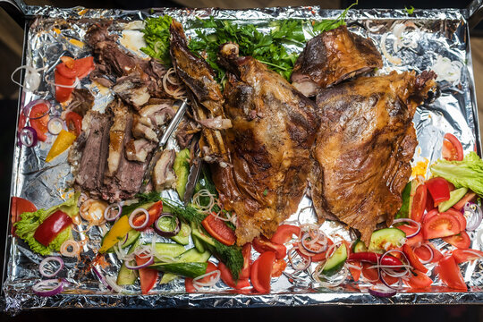 Huge tray with baked pork and fresh vegetables