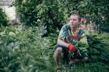A man works in the garden, flying weeds, tending the lawn
