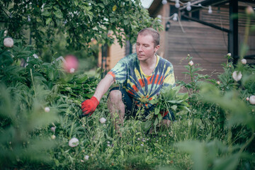 A man works in the garden, flying weeds, tending the lawn