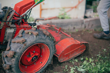 A man works in the garden, plows the soil with a cultivator