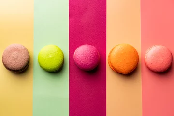 Deurstickers Cookie macaron or macaroon on colorful bright background from above. Multicolored almond cookies with bright shadows, top view © petrrgoskov