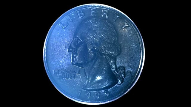 On a black background, quarter dollar coin is glitters in the rays of light. Macro. Closeup
