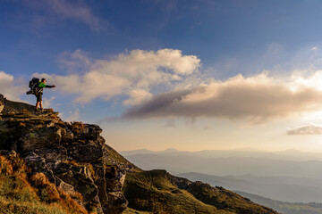A little boy standing on a large rocky rock admires the landscape of the Carpathians, the top of Mount Pip Ivan Chornohirsky.