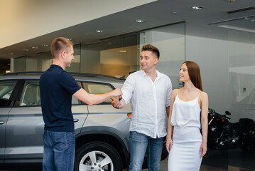 The seller passes the keys to a new car to a young family. Buying a new car
