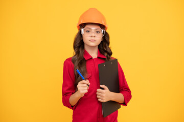 serious child girl in protective hard hat and glasses hold folder with paper documents, examining