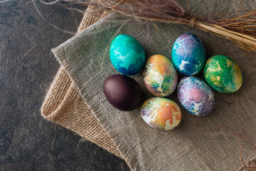 multi-colored Easter eggs of blue tones on a brown cloth background. Top view