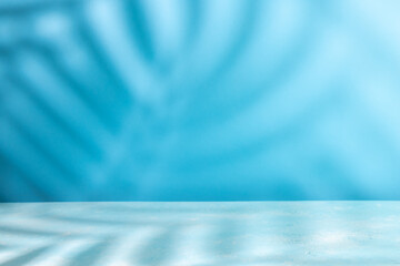 Palm coconut leaf shadow on table top and blue wall background. Abstract summer backdrop with copy space. © Svetlana Kolpakova