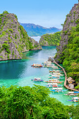 Blue crystal water in paradise Bay with boats on the wooden pier at Kayangan Lake in Coron island,...