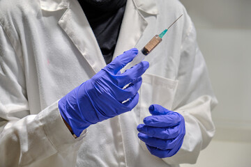 Hand with a latex glove holding a syringe with a covid 19 vaccine.