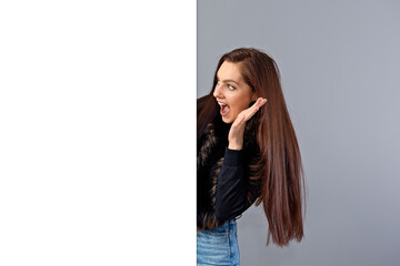 emotional young teenager woman showing blank signboard with copy space, isolated on gray