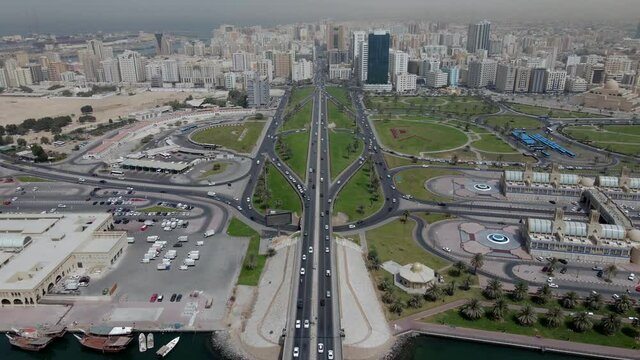 2021: Drone view of Sharjah's Khalid Lake and city skyline on a bright summer day, Sharjah bridge with city traffic, United Arab Emirates. 4k Footage
